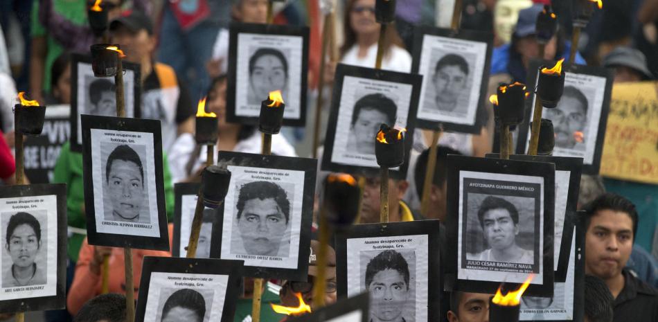 Familiares de 43 estudiantes universitarios de maestros desaparecidos llevan fotos de los estudiantes mientras marchan con simpatizantes para exigir que no se cierre el caso y que se sigan las recomendaciones de los expertos sobre nuevas pistas, en la Ciudad de México, el martes 26 de abril de 2016.