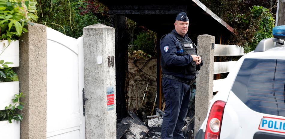 Un oficial de policía municipal se para frente a la casa dañada del alcalde de l'Hay-les-Roses, Vincent Jeanbrun, en l'Hay-les-Roses, un suburbio de París, el 2 de julio de 2023, después de que los alborotadores embistieran un vehículo.