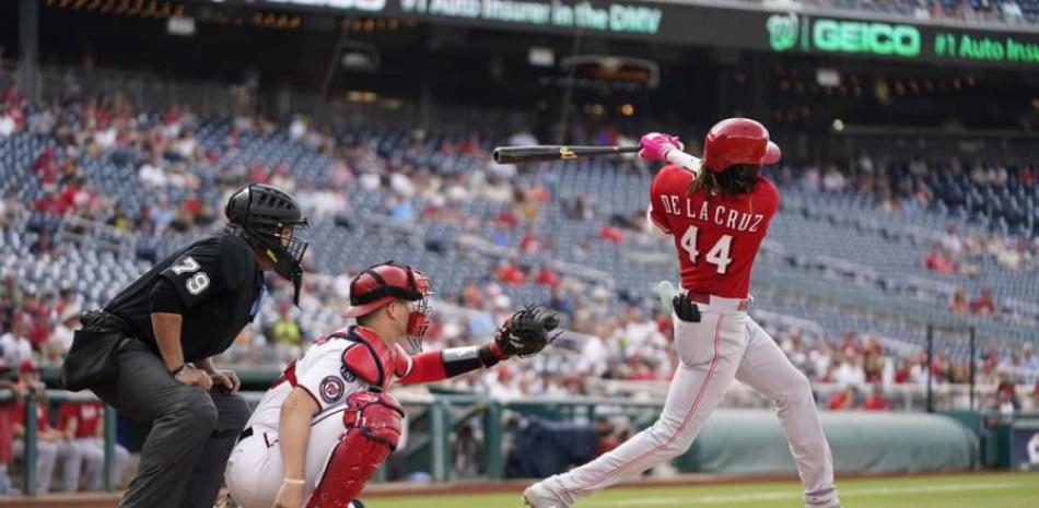 El dominicano de los Rojos de Cincinnati Elly De La Cruz pega un sencillo en el segundo episodio frente al catcher de los Nacionales de Washington Riley Adams y el umpire Manny González.
