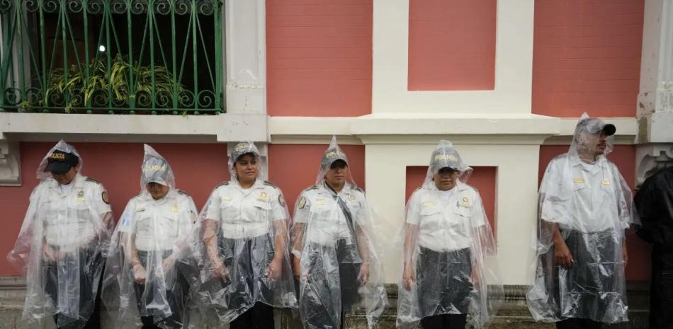 La policía hace guardia fuera del edificio del Tribunal Electoral mientras los manifestantes marchan para apoyar el proceso electoral en la ciudad de Guatemala, en un lluvioso sábado del 8 de julio de 2023.