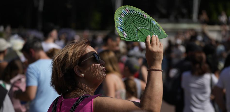 Una turista usa un ventilador para protegerse la cara del sol