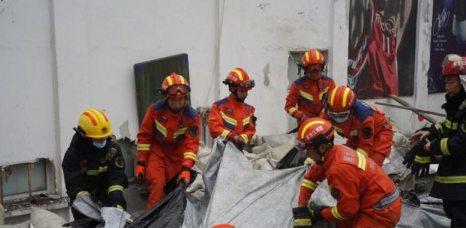 Bomberos durante labor de rescate en derrumbe del techo de un centro deportivo escolar en China