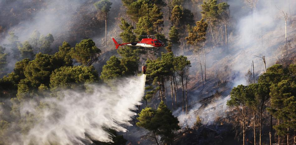 Un helicóptero de extinción de incendios drena agua en un incendio forestal en la montaña en Altofonte cerca de Palermo, Italia