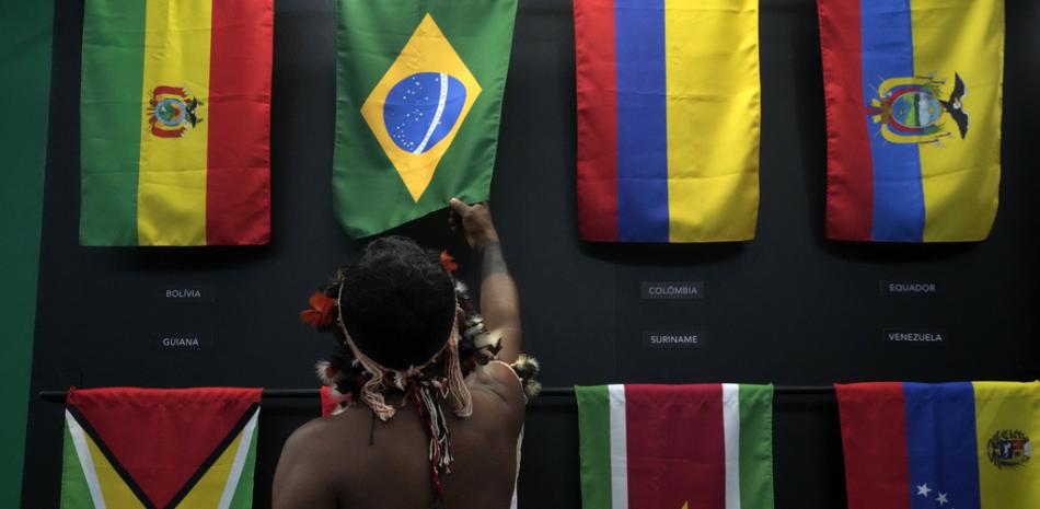 Un indígena pasa su mano sobre la bandera brasileña en un pabellón de banderas de los Estados