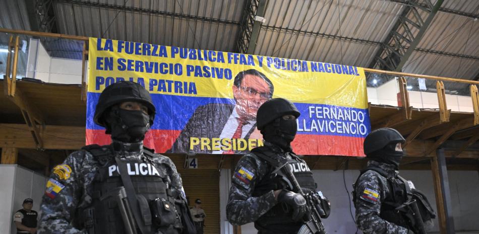 Policías hacen guardia mientras seguidores del candidato Fernando Villavicencio participan en un acto ayer en Quito.