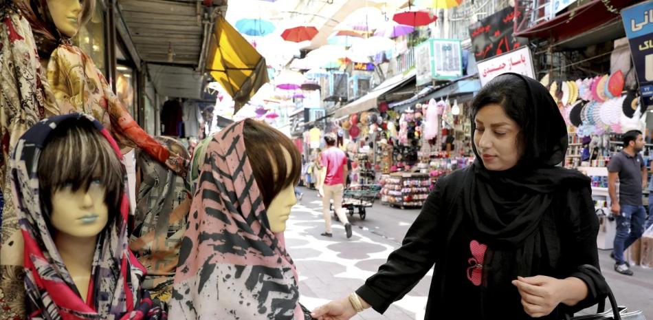 Una mujer inspecciona un pañuelo en la cabeza en un mercado en el centro de Teherán, el 3 de julio de 2019.