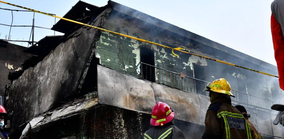 Dos bomberos observan una de las estructuras dañadas por la explosión y el incendio registrado en San Cristóbal