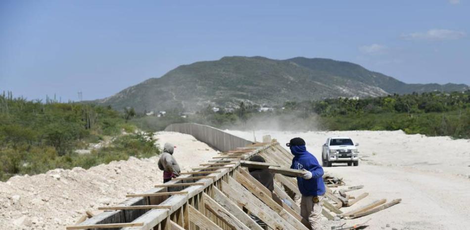 Dos obreros, en la zona de Jimaní, arman una estructura para el vaciado de hormigón armado en uno de los componentes del muro que se levanta a lo largo de la línea fronteriza con Haití.