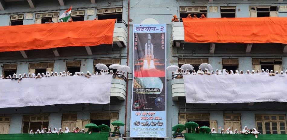 Estudiantes ondean banderas indias en la escuela Anjuman-E-Islam, decorada con los colores de la bandera india y un estandarte de la nave espacial Chandrayaan-3 de la ISRO, en Ahmedabad, el 12 de agosto de 2023, antes de las celebraciones del 76º Día de la Independencia de la India