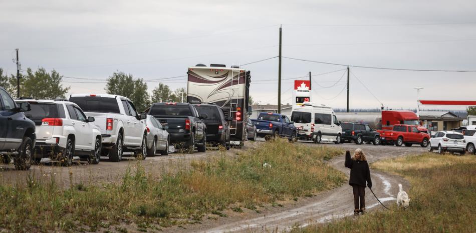Varios vehículos esperan en fila para repostar, en Fort Providence, en los Territorios del Noroeste, Canadá, en la única carretera hacia el sur desde Yellowknife, el 17 de agosto de 2023.