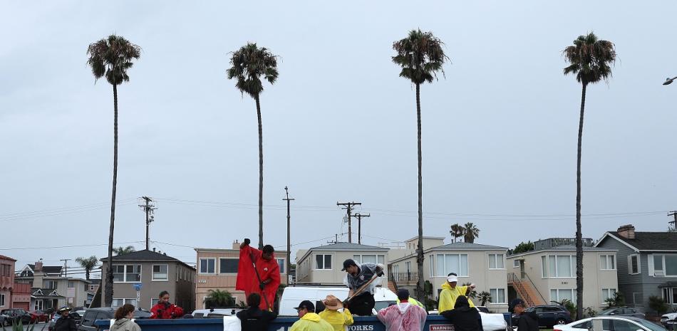 Voluntarios y miembros del Departamento de Bomberos de Long Beach llenan sacos de arena en Belmont Shore Beach el 20 de agosto de 2023 en Long Beach, California.