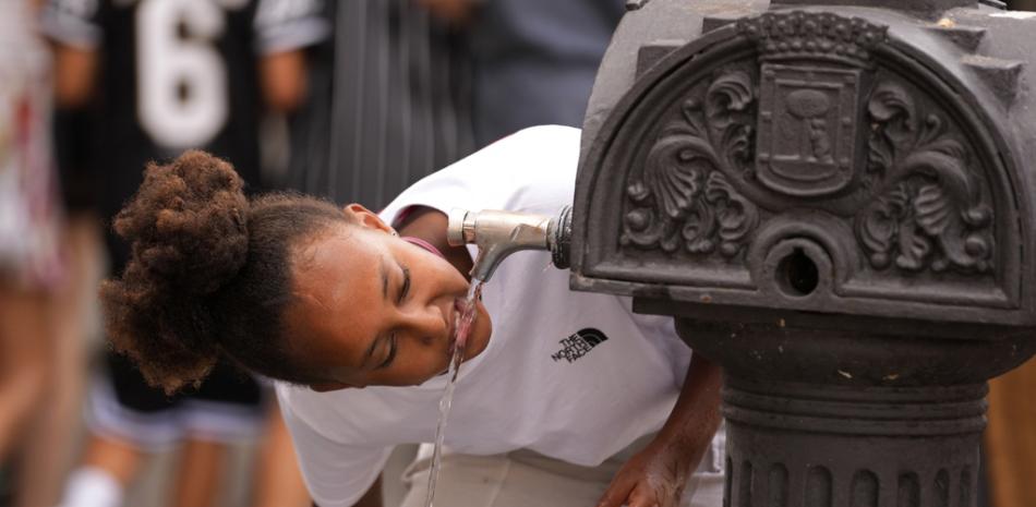 Una niña bebe agua del grifo de una fuente pública en Madrid, España, el 18 de julio de 2023
