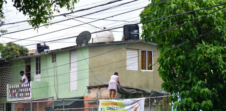 Una señora refuerza el techo de su vivienda para esperar los torrenciales que vienen acompañados con los vientos de tormenta de Franklin.