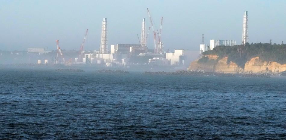 La central nuclear de Fukushima Daiichi, dañada por un enorme terremoto y un tsunami el 11 de marzo de 2011, se ve desde el cercano puerto pesquero de Ukedo en la localidad de Namie, nordeste de Japón, el jueves 24 de agosto de 2023.(AP Foto/Eugene Hoshiko)