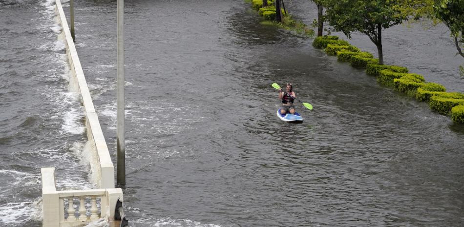 Zeke Pierce monta su tabla de remo en medio de un Bayshore Blvd inundado en el centro de Tampa, Florida