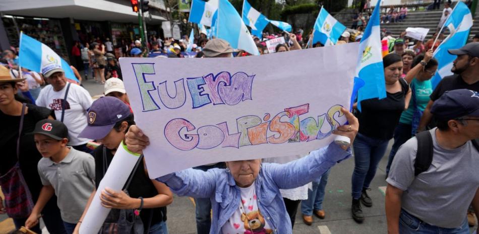 Una mujer sostiene un cartel durante una marcha contra las acciones legales emprendidas por la Fiscalía General contra el partido Movimiento Semilla