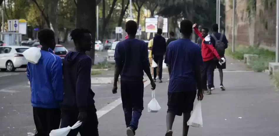 Migrantes caminan hacia un autobús que partirá hacia Marsella, en Roma, 12 de setiembre de 2023.
