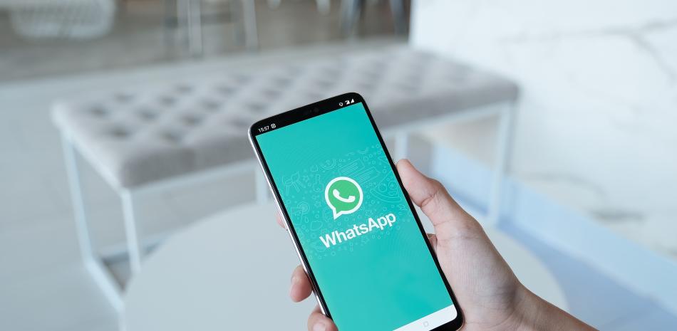 Mujer sosteniendo un Oneplus 6 y abriendo una tienda de aplicaciones buscando el servicio social de Internet WhatsApp en la pantalla.