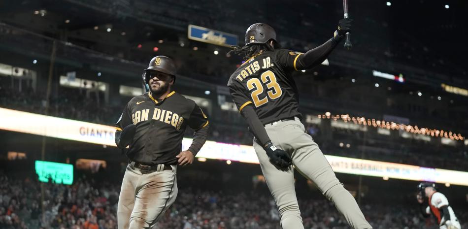 Trent Grisham, de los Padres de San Diego, corre hacia el dominicano Fernando Tatis Jr., luego de anotar ante los Gigantes de San Francisco, el miércoles 27 de septiembre de 2023 (AP Foto/Jeff Chiu)