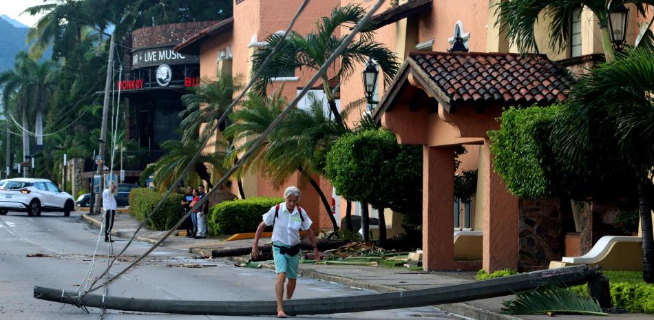Un hombre camina por una calle con postes de luz caídos después del paso del huracán Lidia en Puerto Vallarta, estado de Jalisco, México, el 11 de octubre de 2023.