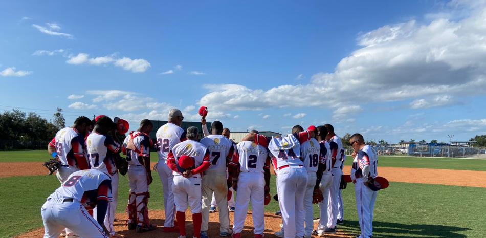 Grupo de jugadores oran luego de conseguir su primera victoria en el Mundial de Béisbol para Veteranos.