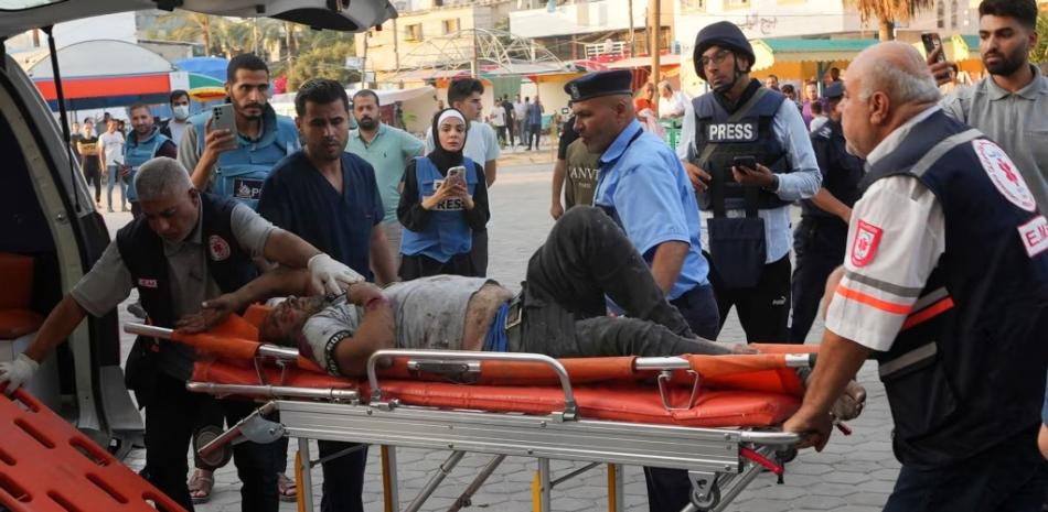 Periodistas observan el traslado de un palestino herido por bombardeos israelíes en Gaza.