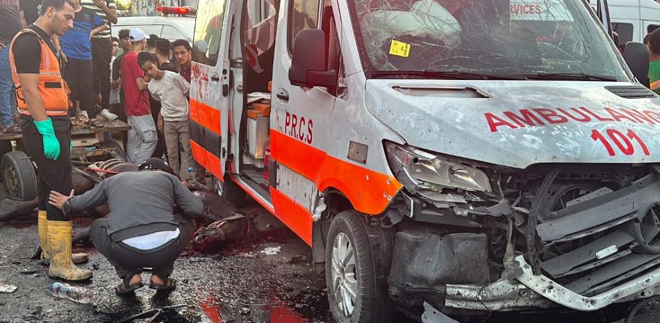 Un caballo muerto yace en el suelo mientras la gente se reúne alrededor de una ambulancia dañada en un ataque israelí frente al hospital Al-Shifa en Gaza el 3 de noviembre de 2023.