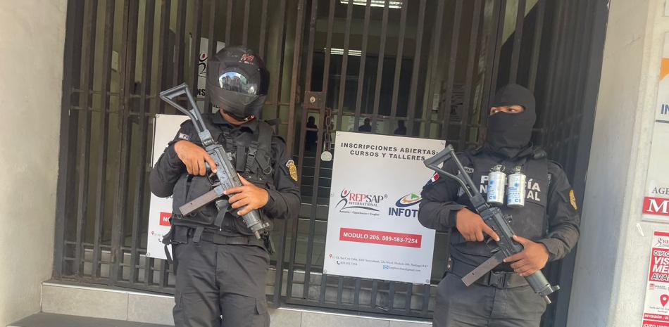 Elementos de la Policia Nacional custodian una puerta de un centro comercial, como parte de los allanamientos que se han realizado este jueves en Santiago.