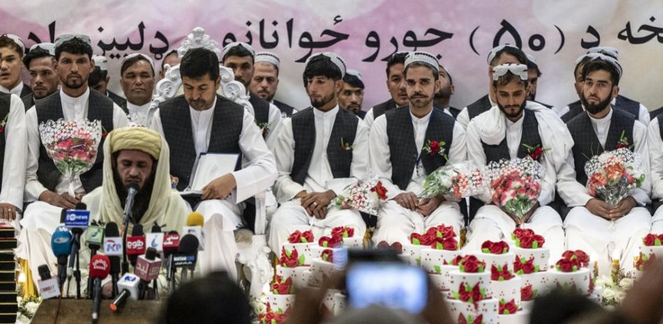 Los novios afganos observan durante una ceremonia de boda masiva en un salón de bodas en Kabul el 25 de diciembre de 2023.