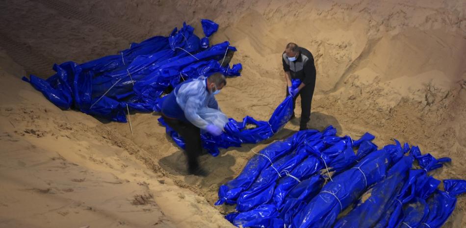 Los cadáveres amortajados de palestinos asesinados en el norte de Gaza son enterrados en una fosa común en Rafah, en el sur de la Franja de Gaza, el 26 de diciembre de 2023
