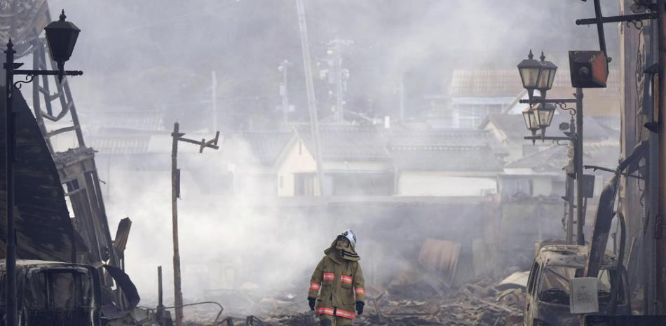 Un bombero camina entre los escombros y los restos de un incendio en un mercado, luego de un terremoto