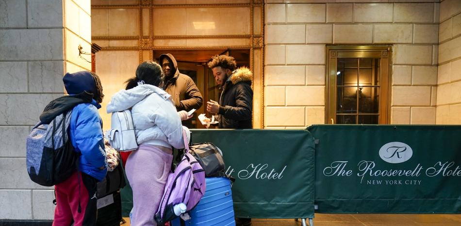 Una familia de migrantes muestra su documentación a los guardias de seguridad en el Hotel Roosevelt, el martes 9 de enero de 2024, en la ciudad de Nueva York.