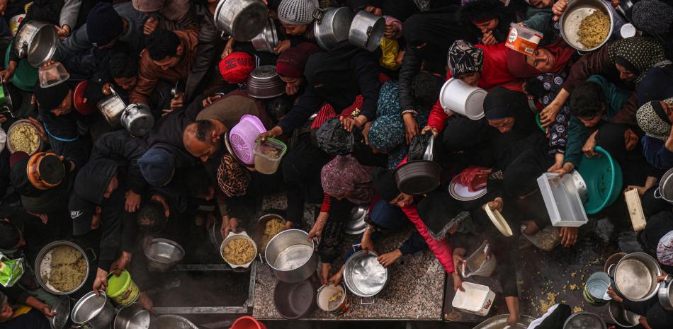 Palestinos reciben alimentos en un punto de donación en un campamento para desplazados en Rafah.