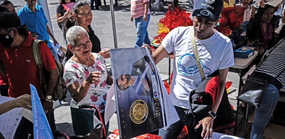 Simpatizantes del presidente salvadoreño y candidato presidencial a la reelección Nayib Bukele, reciben calendarios en una plaza en el centro histórico de San Salvador el 31 de enero de 2024..foto Yuri CORTEZ