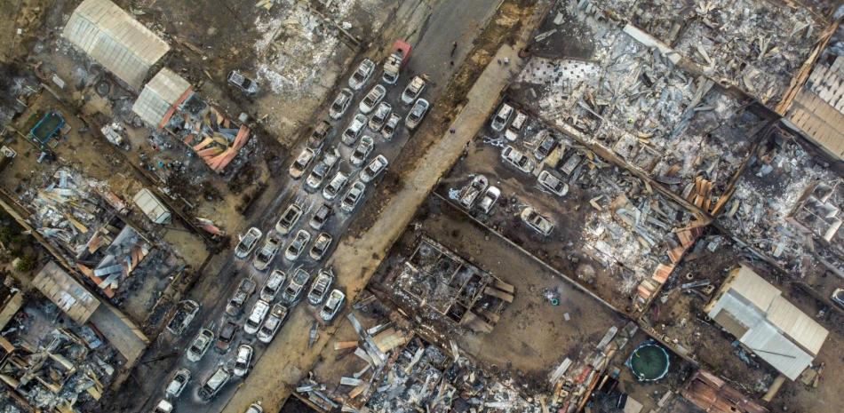 Autos quemados yacen en una calle después de que un incendio forestal alcanzara el barrio Villa Independencia en Viña del Mar, Chile, el sábado 3 de febrero de 2024.