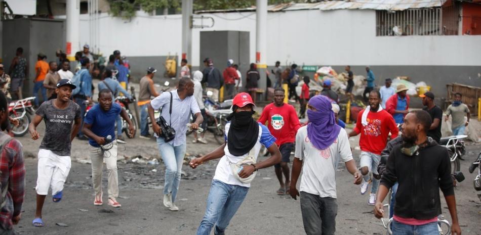 Los manifestantes corren en busca de refugio después de que la policía abriera fuego para dispersar a la multitud durante una manifestación que exigía la renuncia del primer ministro Ariel Henry.