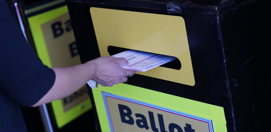 Una persona deposita papeletas de voto por correo en un buzón de entrega de papeletas de voto por correo en el departamento electoral del condado de Clark, en Las Vegas.