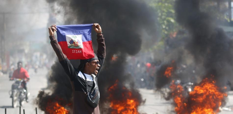 Un haitiano levanta una bandera en medio de las protestas que se realizan este fin de semana en ese país.
