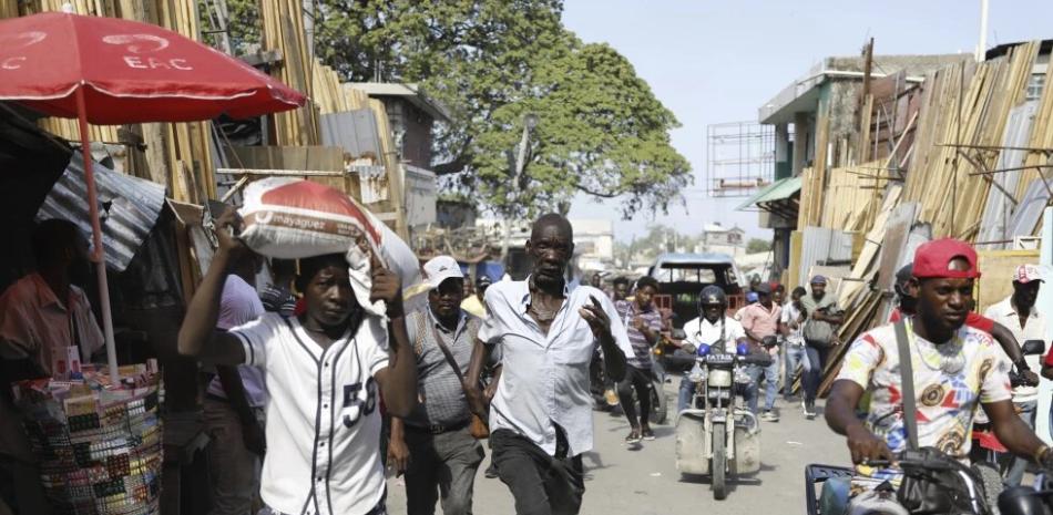 Los peatones corren a refugiarse después de escuchar disparos en Puerto Príncipe, Haití, el jueves 7 de marzo de 2024.