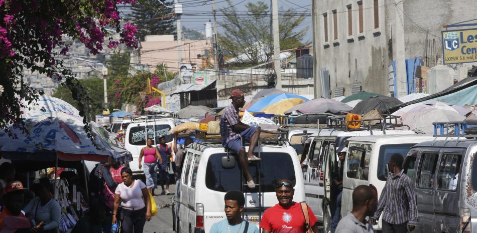 Vista de peatones y tráfico en una calle de Puerto Príncipe, Haití, 12 de marzo de 2024. Una propuesta para instalar un gobierno provisional en Haití parecía colapsar el miércoles 13 de marzo de 2024 cuando algunos partidos políticos rechazaron el plan de crear un consejo presidencial para administrar la transición.(AP Foto/Odelyn Joseph)