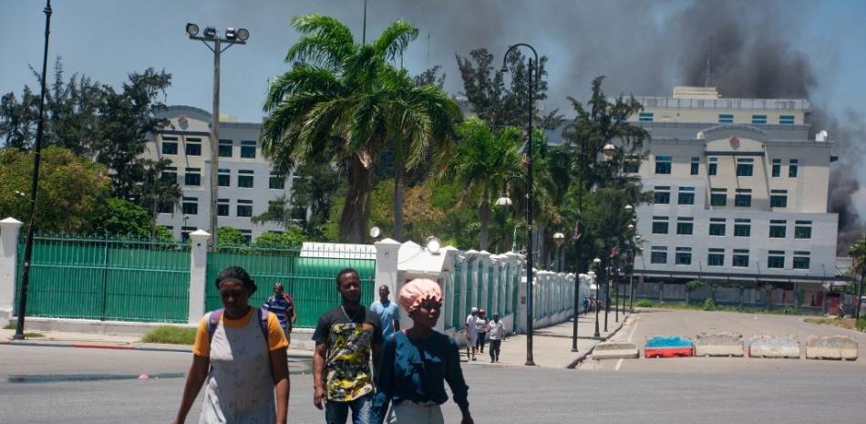 Mientras sale humo del edificio del Ministerio de Finanzas, personas abandona la zona tras oír disparos de bandas armadas cerca del Palacio Nacional en Puerto Príncipe, Haití, el 2 de abril de 2024