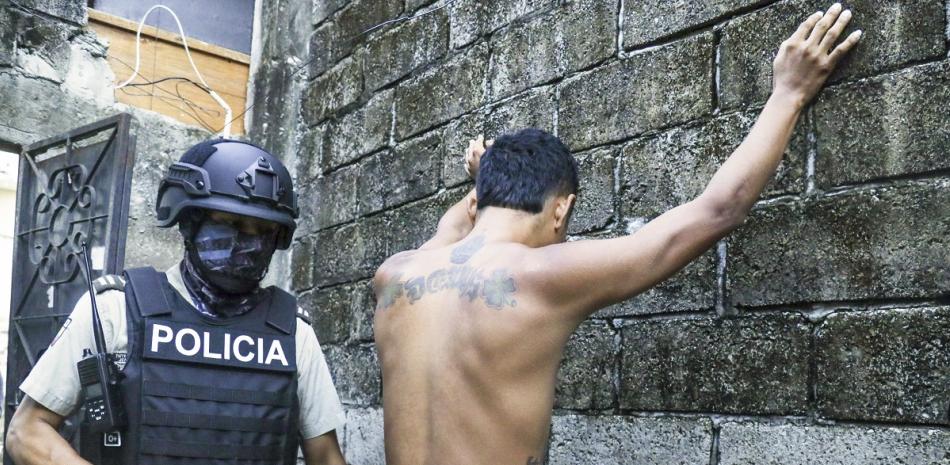 Un hombre levanta los brazos contra la pared mientras la policía revisa si lleva armas o drogas, en Guayaquil, ayer.