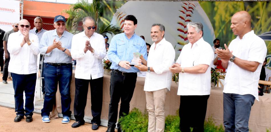 Julio Virgilio Brache Álvarez entrega una placa a Junior Noboa, mientras aplauden, desde la izquierda, Braulio Brache, Luis Mejía, Juan Marichal y desde la derecha Moisés Alou y Winston Llenas, en la apertura del béisbol RBI de Villa Altagracia el sábado13 de abril en el club Los Prados.