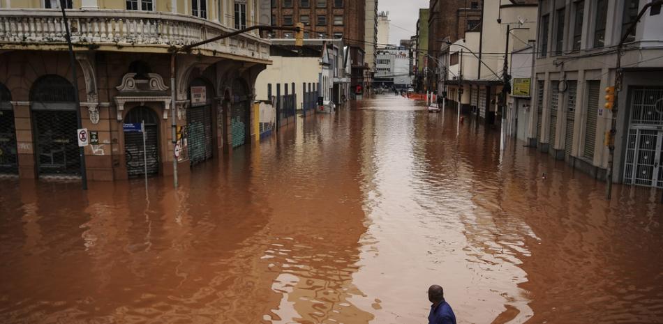 Un hombre camina por una calle inundada debido a las intensas lluvias