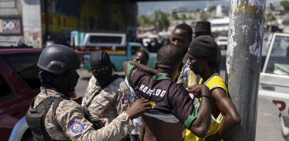 policía inspecciona a un hombre en busca de armas, en Puerto Príncipe