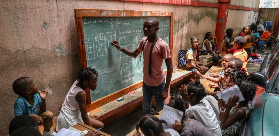 Un maestro enseña matemáticas a niños que viven en un refugio para familias que huyeron de sus hogares debido a la violencia de las pandillas, en Puerto Príncipe.