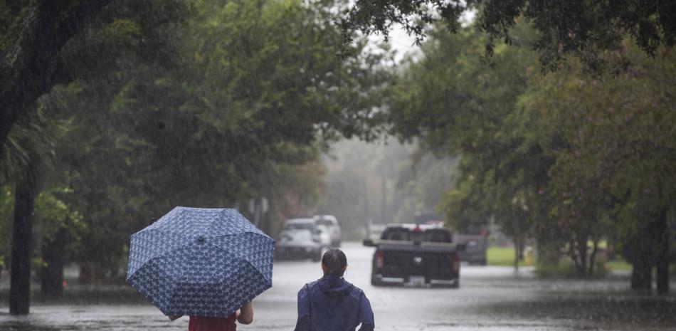 La gente se adentra en las aguas de la inundación que superan Gordon Street mientras continúa lloviendo debido a la tormenta tropical Debby, el martes 6 de agosto de 2024, en Charleston, Carolina del Sur.