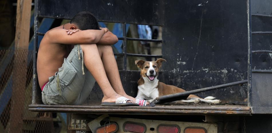 Un hombre detenido por agentes de la policía fronteriza durante una operación contra el tráfico de migrantes espera en un camión junto a un perro antes de ser trasladado cerca de Santa Fe, provincia de Darién, Panamá, el 7 de agosto de 2024.