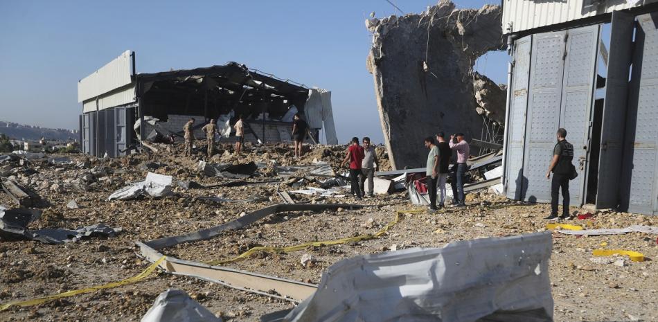 Un grupo de personas se congregan junto a un hangar alcanzado por un ataque aéreo israelí, en Jiyeh, Líbano, ayer.