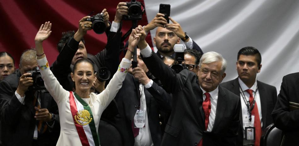 El nuevo Presidente de México, Claudia Sheinbaum (L) y el Presidente saliente de México, Andrés Manuel López Obrador, saludan a los asistentes (Photo by Alfredo ESTRELLA / AFP)